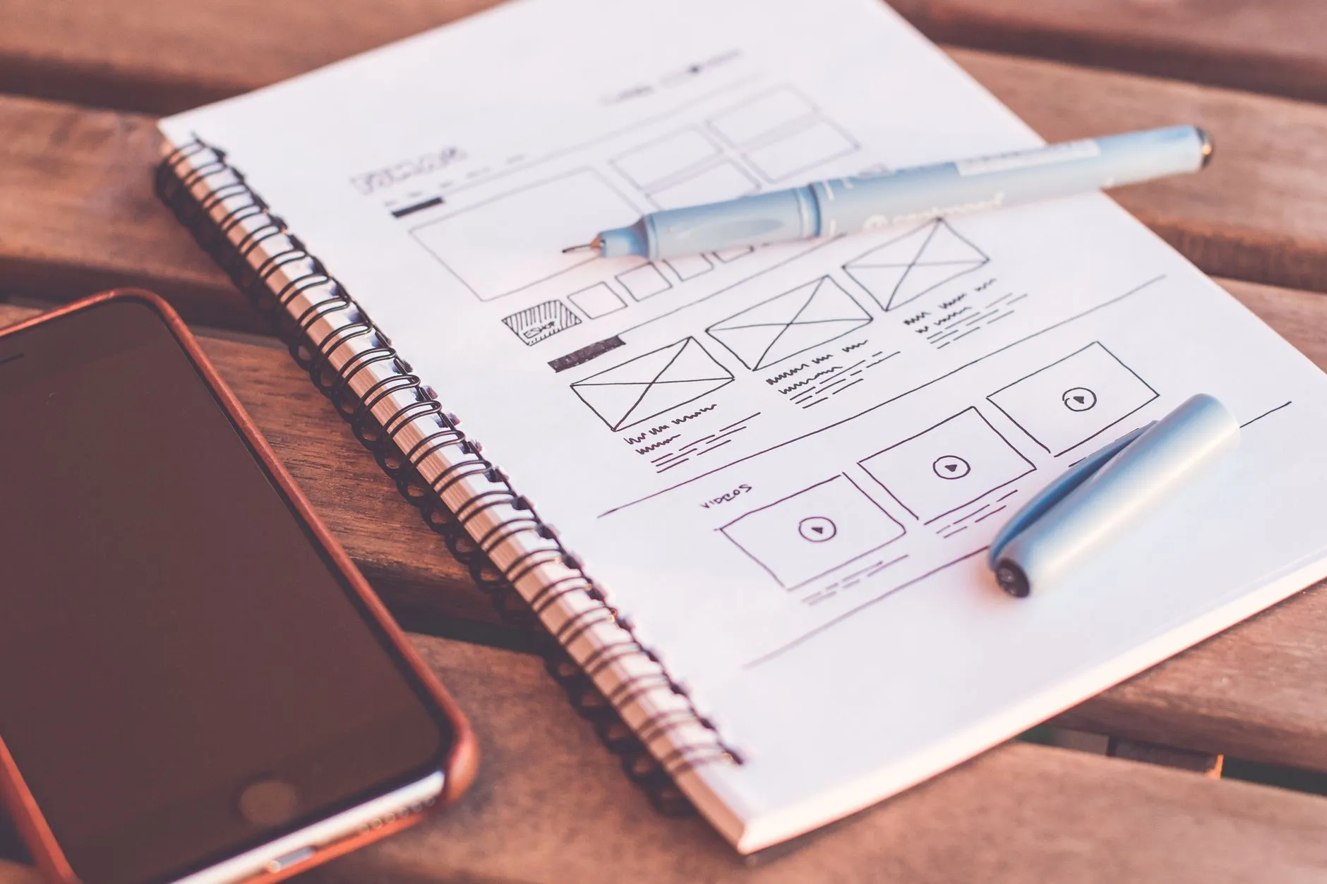Notebook, smartphone, and interface planning materials arranged on a design desk